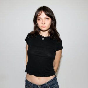 Clementine Creevy of Cherry Glazerr standing in front of a plain grey background.