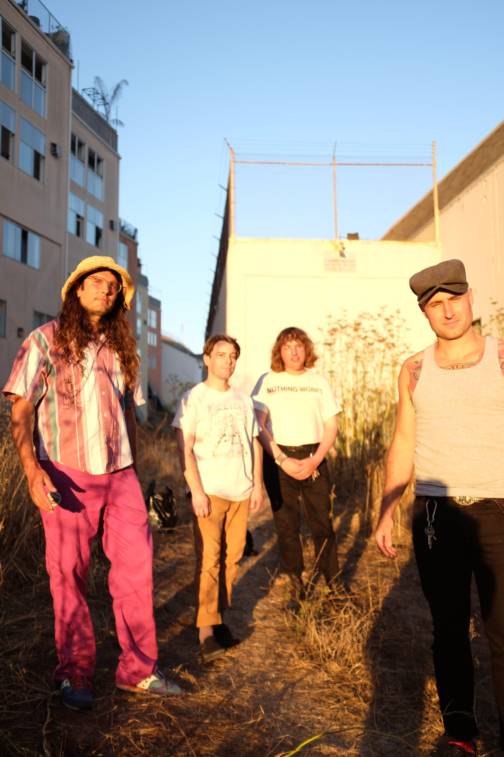 Four members of Sutros standing outside in the bright sun between buildings